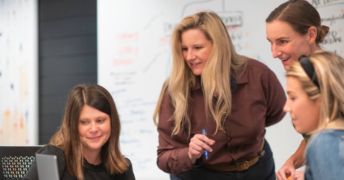 Women discussing strategy by whiteboard