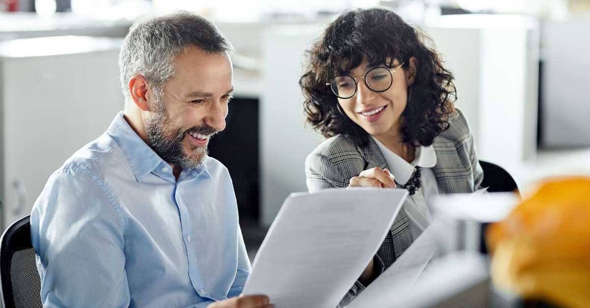 Male and female colleague reviewing document and smiling
