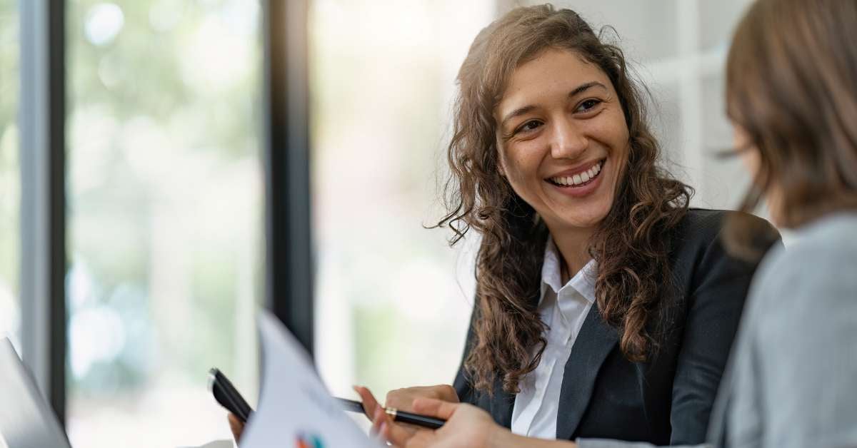 Female leader smiling at teammate while reviewing document