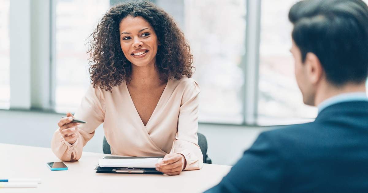 Woman seated at table speaking with male colleague