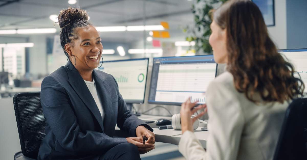 Women speaking animatedly at desk